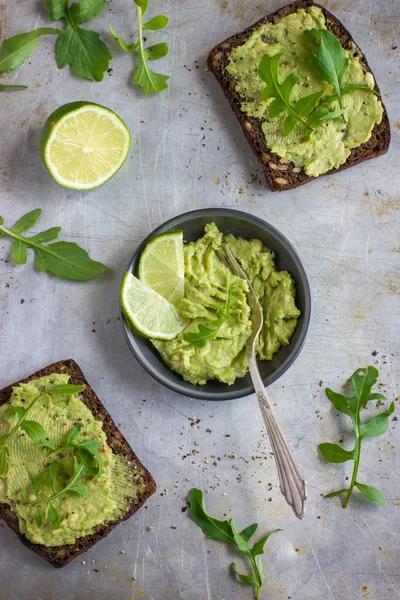 Rye toasts with guacamole and arugula on rustic  background — Stok Foto