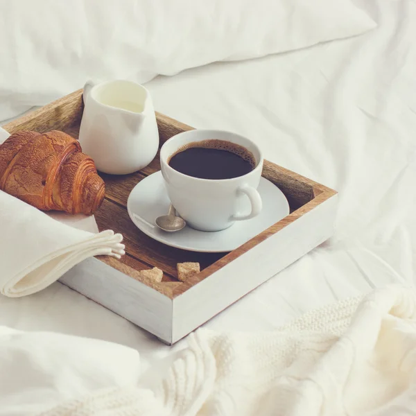 Śniadanie w złych, taca z filiżanką kawy i rogalika — Zdjęcie stockowe