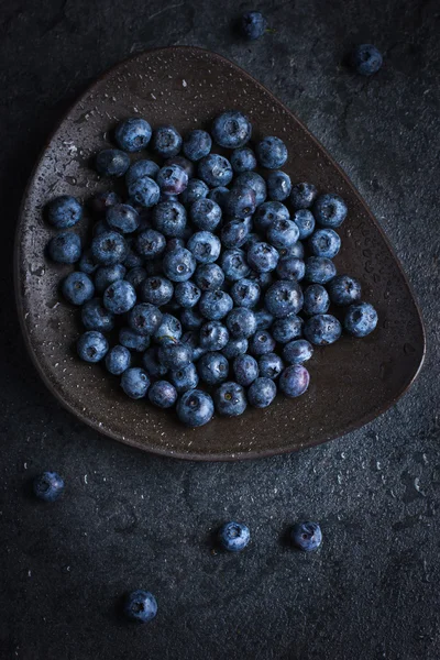 Fresh blueberry on black plate with water drops — Stock Photo, Image