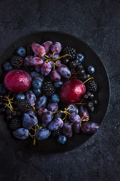 Frutas y bayas oscuras frescas sobre fondo negro . —  Fotos de Stock