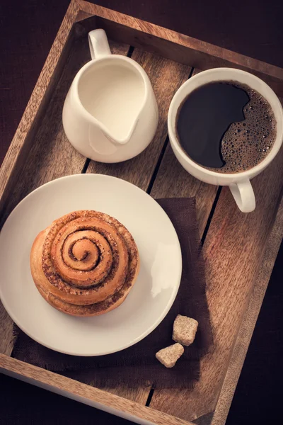 Rouleau de cannelle, tasse de café et crème sur plateau en bois — Photo