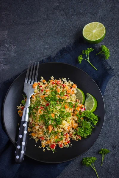 Cuscuz com legumes e salsa em prato preto — Fotografia de Stock