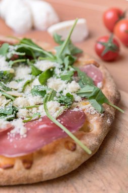 Çiğ jambon ve fesleğenli bir pizzanın yakın çekimi..