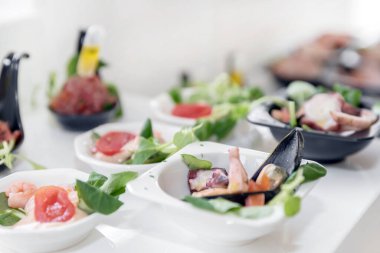 Açık büfe masasında hafif deniz ürünleri atıştırmalıkları. Etkinlikte çeşitli mini yemekler, atıştırmalıklar, restoran deniz ürünleri. Düğün partisi. Gala resepsiyonu. Parti malzemeleri için süslenmiş nefis bir masa..