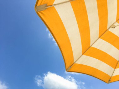 Güneşli bir günde sarı plaj şemsiyesi. Kumsalda parlak renkli şemsiye.