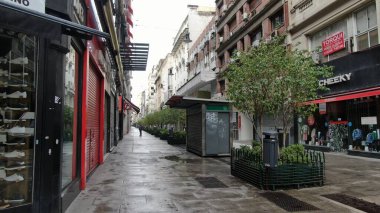 Buenos Aires, Arjantin 'in Buenos Aires şehir merkezindeki boş bir caddenin geniş açıyla görüntüsü. Sahnede, dükkanlar ve yerleşim birimleri de dahil olmak üzere caddenin her iki tarafını kaplayan yüksek binalar yer alıyor.. 