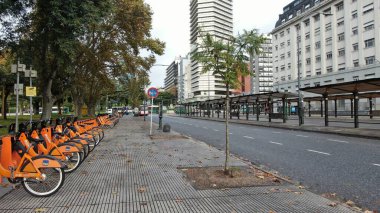 Buenos Aires, Arjantin 'in Buenos Aires şehir merkezindeki boş bir caddenin geniş açıyla görüntüsü. Sahnede, dükkanlar ve konut birimleri de dahil olmak üzere caddenin her iki tarafını kaplayan yüksek binalar yer alıyor. Belirgin işaretler