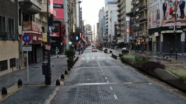 Buenos Aires, Arjantin 'in Buenos Aires şehir merkezindeki boş bir caddenin geniş açıyla görüntüsü. Olay yerinde dükkanlar ve konut birimleri de dahil olmak üzere yüksek binalar yer alıyor.