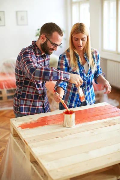 Young couple painting furniture at home