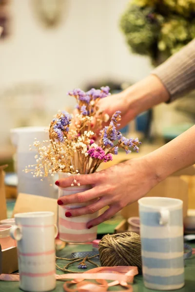 Женщина кладет сухие цветы в вазу — стоковое фото