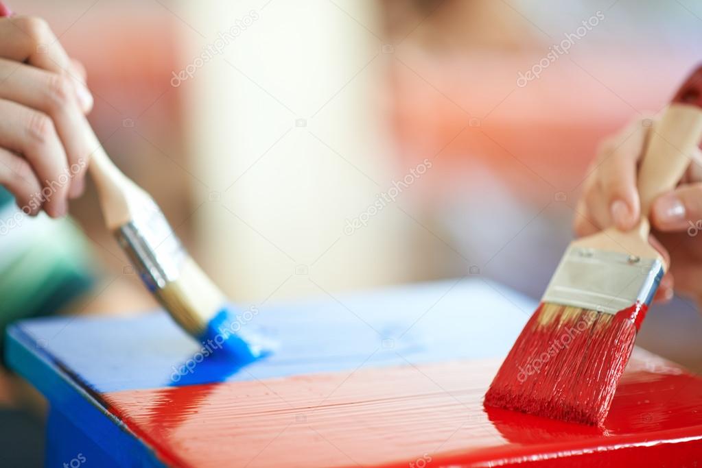 Couple painting furniture in red and blue colour