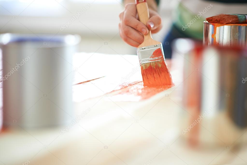 Woman painting furniture with paint brush