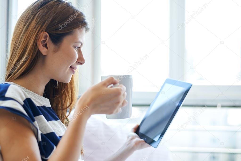 woman in bed looking in tablet