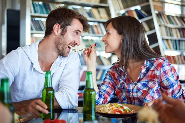 Couple eating spaghetti and cheers with beer — Stock Photo, Image
