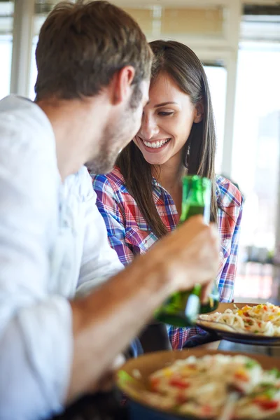 Couple eating spaghetti and cheers with beer — Stock Photo, Image