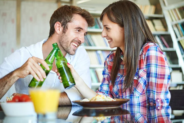 Couple eating spaghetti and cheers with beer — Stock Photo, Image