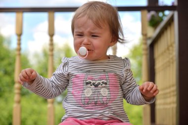 Emzik takmış küçük bir kız ağlıyordu ahşap verandada