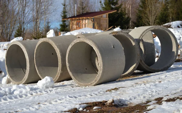 Large concrete pipes for well in village on sunny winter day