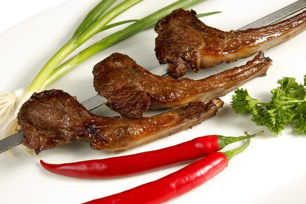 Maydanoz, kırmızı biber ve soğan beyaz plaka üzerinde şiş kebap
