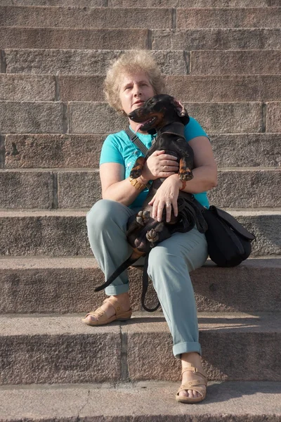 Mujer de mediana edad sosteniendo dachshund en las escaleras —  Fotos de Stock