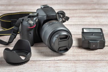 Ahşap zeminde fotoğraf makinesi ve flaş var.