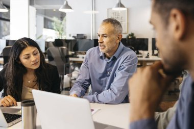 Çeşitli iş adamları modern bir çalışma alanında tartışıyorlar ve birlikte çalışıyorlar.