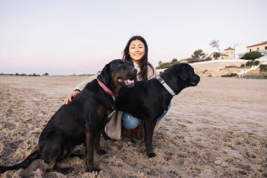 Genç bir kadın gülümsüyor, kumsalda yoldaşlarıyla vakit geçiriyor.