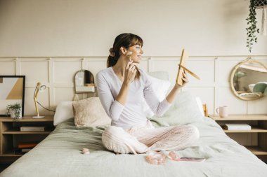 Sabah güzellik rutini sırasında cilde yüz silindiri süren bir kadın.