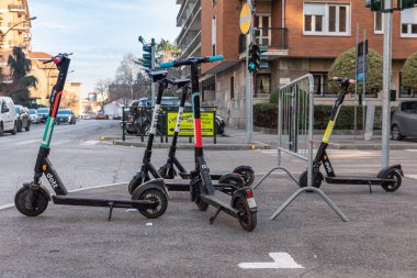 Collegno, İtalya. 15 Şubat 2021. Bir grup elektrikli scooter kaldırıma park etmiş. Uygulama ile scooter 'ı kiralanabilir hale getirmek için park işareti olan istasyon toplanıyor.