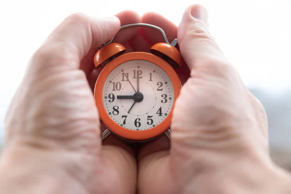 ヤシの中に小さなオレンジ色の目覚まし時計を持って白人男性の手 時間の概念 — ストック写真