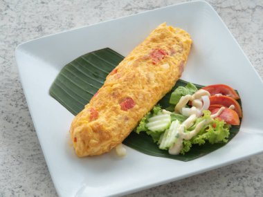 Kahvaltıda salatalık, domates ve mayonez ile servis edilen jambonlu omlet..