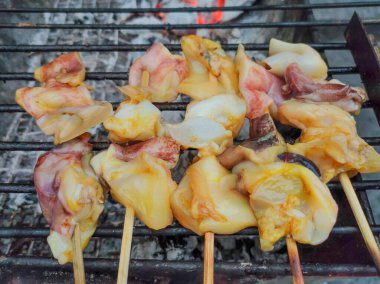 Baharat soslu dilimlenmiş kalamar ocakta ızgara yapmaya hazır. Barbekü için taze kalamar şişleri..
