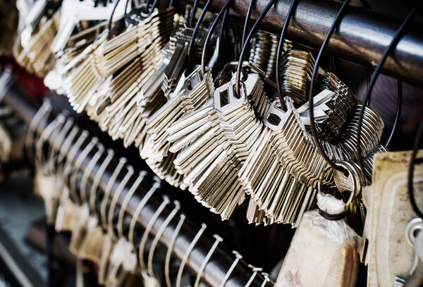 Куча ключей висит на крючках на стальной балке
