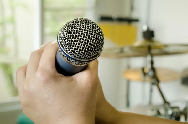 Hands holding a microphone in music room — Stock Photo, Image