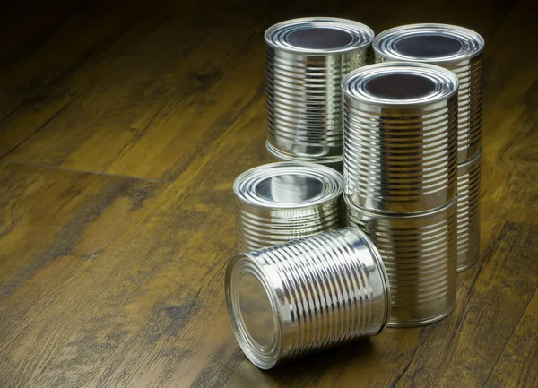 Blikjes voor de menselijke voeding op houten achtergrond — Stockfoto