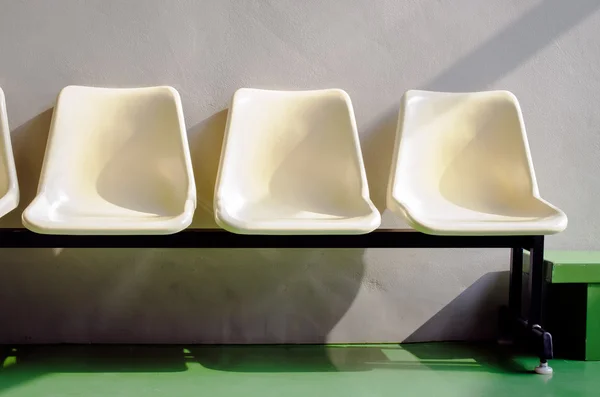 Set van witte plastic stoelen permanent voor grijs cement muur — Stockfoto
