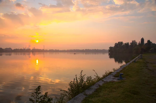 Sonbaharda bir gölün üzerinde gün doğumu sisle