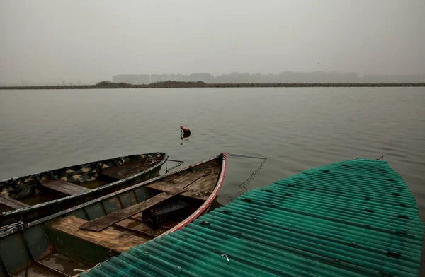 Sonbaharda sisli bir günde nehir kıyısında tekne.