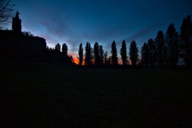 Sonbaharda günbatımında selvi ile çevrili bir kilisenin arkasındaki açık alan.