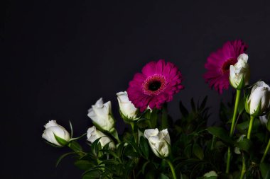 Beyaz güller, kasımpatılar, mor gerberalar ve siyah arka planda güller.
