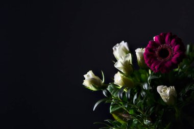 Beyaz güller, kasımpatılar, mor gerberalar ve siyah arka planda güller.