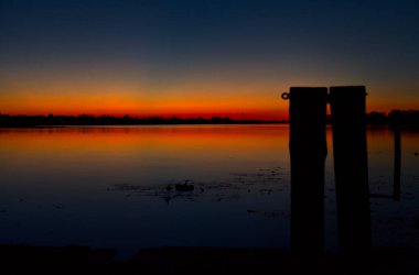Sonbaharda gün batımında bir gölün iskelesinde