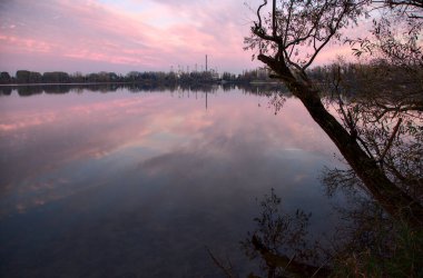 Sonbaharda günbatımında gölün kıyısındaki ağaçlar ve kayalar