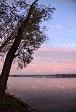 Sonbaharda günbatımında gölün kıyısındaki ağaçlar ve kayalar