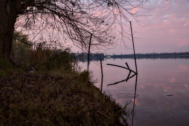Sonbaharda günbatımında gölün kıyısındaki ağaçlar ve kayalar
