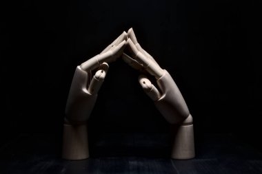 Parmak uçlarından birbirine dokunan iki tahta el.