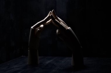 Parmak uçlarından birbirine dokunan iki tahta el.