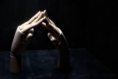 Parmak uçlarından birbirine dokunan iki tahta el.