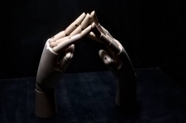 Parmak uçlarından birbirine dokunan iki tahta el.