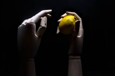 Biri limonu ararken diğeri limonu tutan tahta bir el.